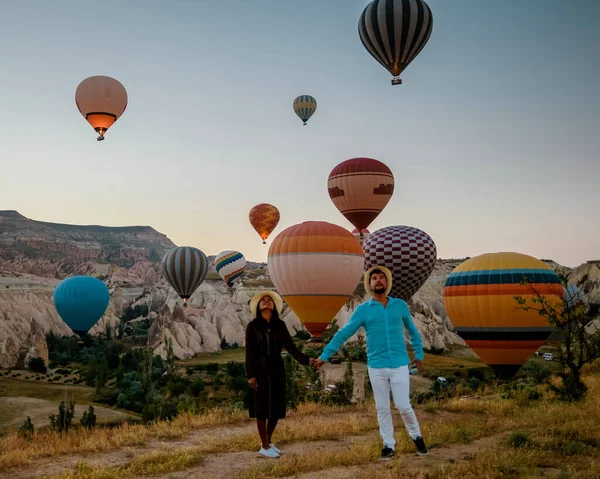 Cappadoce Turquie au lever du soleil, couple hommes et femmes d'âge moyen en vacances dans les collines de Goreme Capadoce Turquie, hommes et femmes à la recherche de soleil se lever avec des montgolfières en Cappadoce — Photo