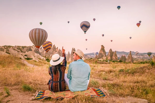 Cappadocia Turchia all'alba, coppia di uomini e donne di mezza età in vacanza sulle colline di Goreme Capadocia Turchia, uomini e donne in cerca di sunrsise con mongolfiere in Cappadocia — Foto Stock