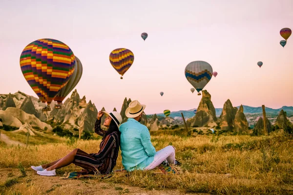 Kappadokien Turkiet under soluppgången, par medelålders män och kvinnor på semester i bergen i Goreme Capadokien Turkiet, män och kvinnor ser solsken med varmluftsballonger i Kappadokien — Stockfoto