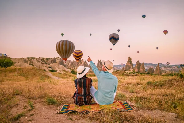 Cappadocia Turkey during sunrise, couple mid age men and woman on vacation in the hills of Goreme Capadocia Turkey, men and woman looking sunrsise with hot air balloons in Cappadocia — Stock Photo, Image