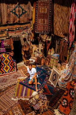 Kapadokya 'daki Kapadokya mağara evindeki eski bir Türk halı dükkanında genç bir turist.