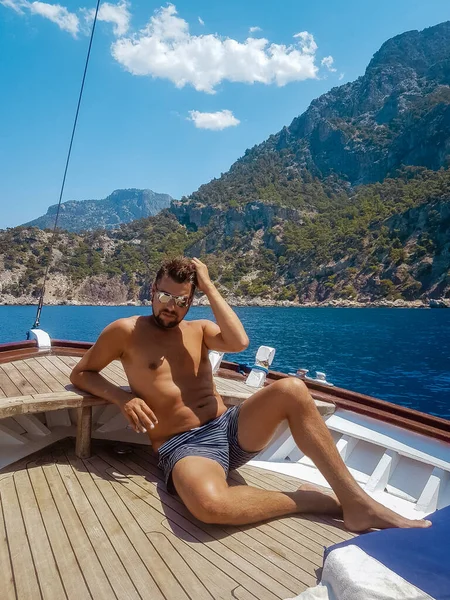 Fethiye Türkiye 'deki Kelebek plajına tekne gezisi sırasında tahta bir teknede dinlenen genç adam, mayo giymiş bronzlaşmış genç çocuk — Stok fotoğraf