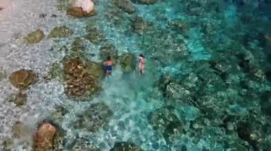 Sardinya Adası İtalya Orosei kıyıları, plaj şemsiyeleriyle dolu güzel bir sahil manzarası, güneşlenen ve turkuaz bir suda yüzen insanlar. Cala Gonone, Sardinya, İtalya, Cala Mariolu