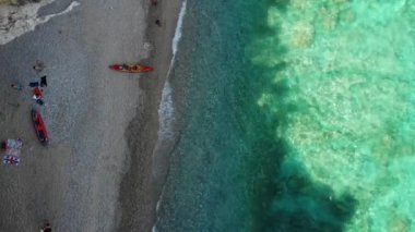 Sardinya Adası İtalya Orosei kıyıları, plaj şemsiyeleriyle dolu güzel bir sahil manzarası, güneşlenen ve turkuaz bir suda yüzen insanlar. Cala Gonone, Sardinya, İtalya, Cala Mariolu