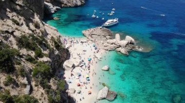Sardinya Adası İtalya Orosei kıyıları, plaj şemsiyeleriyle dolu güzel bir sahil manzarası, güneşlenen ve turkuaz bir suda yüzen insanlar. Cala Gonone, Sardinya, İtalya, Cala Mariolu