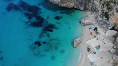 Sardinya Adası İtalya Orosei kıyıları, plaj şemsiyeleriyle dolu güzel bir sahil manzarası, güneşlenen ve turkuaz bir suda yüzen insanlar. Cala Gonone, Sardinya, İtalya, Cala Mariolu