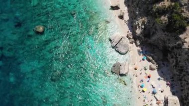 Sardinya Adası İtalya Orosei kıyıları, plaj şemsiyeleriyle dolu güzel bir sahil manzarası, güneşlenen ve turkuaz bir suda yüzen insanlar. Cala Gonone, Sardinya, İtalya, Cala Mariolu