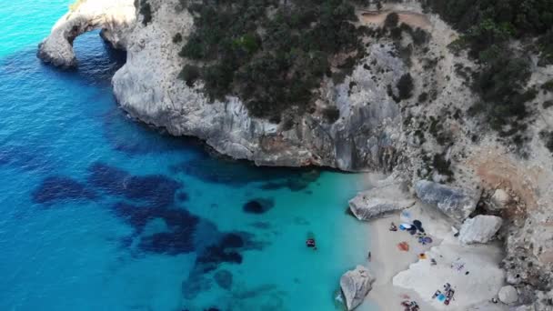 Ilha da Sardenha Itália Costa rosei, vista de uma bela praia cheia de guarda-sóis de praia e pessoas tomando banho de sol e nadando em uma água azul-turquesa. Cala Gonone, Sardenha, Itália, Cala Mariolu — Vídeo de Stock