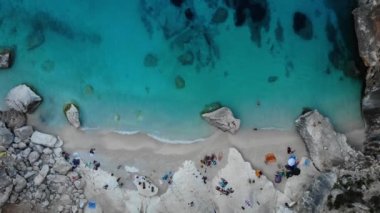 Sardinya Adası İtalya Orosei kıyıları, plaj şemsiyeleriyle dolu güzel bir sahil manzarası, güneşlenen ve turkuaz bir suda yüzen insanlar. Cala Gonone, Sardinya, İtalya, Cala Mariolu