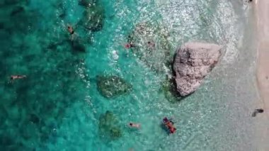 Sardinya Adası İtalya Orosei kıyıları, plaj şemsiyeleriyle dolu güzel bir sahil manzarası, güneşlenen ve turkuaz bir suda yüzen insanlar. Cala Gonone, Sardinya, İtalya, Cala Mariolu
