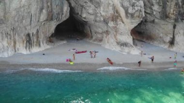 Sardinya Adası İtalya Orosei kıyıları, plaj şemsiyeleriyle dolu güzel bir sahil manzarası, güneşlenen ve turkuaz bir suda yüzen insanlar. Cala Gonone, Sardinya, İtalya, Cala Mariolu