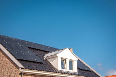 Hollanda 'da güneş panelleri çatıda güneşli bir gökyüzüne bağlı yeni evler inşa edildi. Siyah güneş panellerini kapatın.