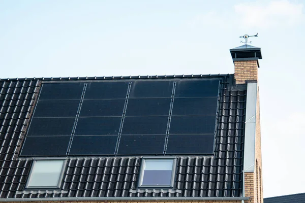 Newly build houses in the Netherlands with solar panels attached on the roof against a sunny sky Close up of new building black solar panels