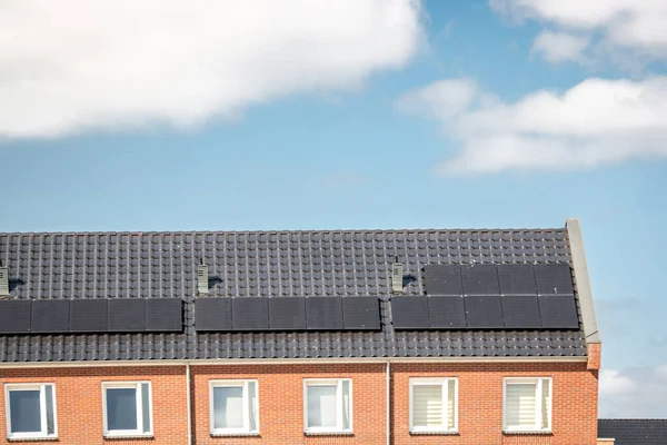 Nově postavené domy v Nizozemsku se solárními panely připevněnými na střeše proti slunné obloze Close up of new building black solar panels — Stock fotografie