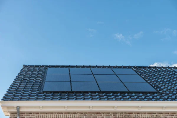 Casa di recente costruzione nei Paesi Bassi con pannelli solari attaccati sul tetto contro un cielo soleggiato Close up of new building black solar panels — Foto Stock