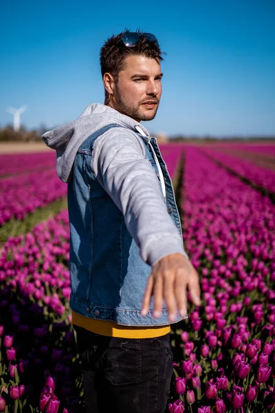 Dutch tulip field, man in tulips field Netherlands,happy young guy in pink flower field