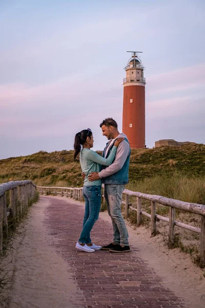 Texel latarnia morska podczas zachodu słońca Holandia Dutch Island Texel, para odwiedzić latarnię morską, mężczyźni i kobieta na wakacjach Texel — Zdjęcie stockowe