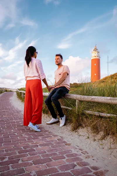 Texel latarnia morska podczas zachodu słońca Holandia Dutch Island Texel, para odwiedzić latarnię morską, mężczyźni i kobieta na wakacjach Texel — Zdjęcie stockowe