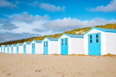 Texel Adası Hollanda, plajda mavi beyaz bir sahil kulübesi, arka planda Texel Holland 'ın kum tepeleri, sahilde bir kulübe.