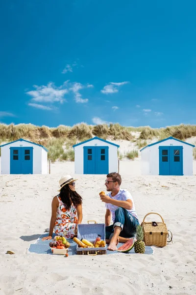 Piquenique na praia Texel Holanda, casal fazendo piquenique na praia de Texel com areia branca e casa colorida — Fotografia de Stock