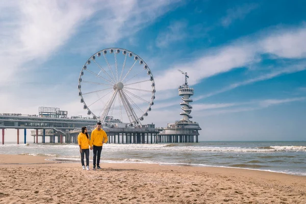 Pareja en la playa de Schevening Países Bajos durante la primavera, La noria El muelle en Scheveningen en Países Bajos, Soleado día de primavera en la playa —  Fotos de Stock