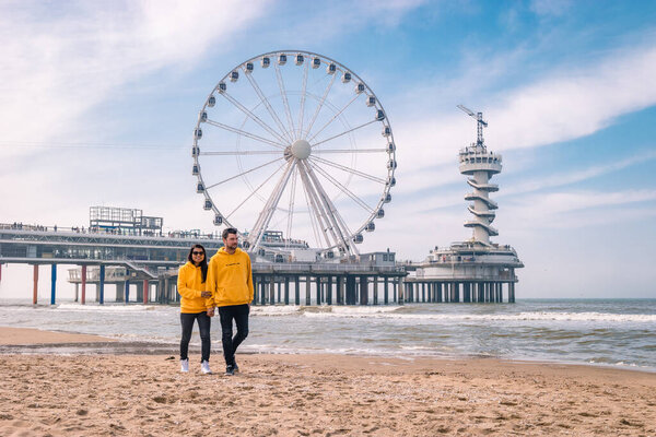 couple on the beach of Schevening Netherlands during Spring, The Ferris Wheel The Pier at Scheveningen in Netherlands, Sunny spring day at the beach