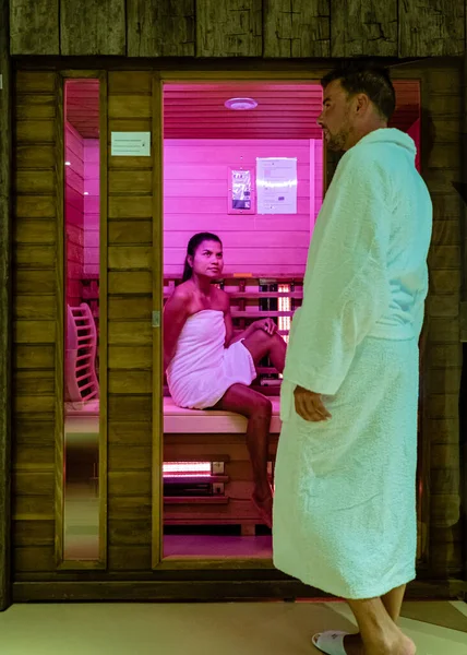 Casal na sauna, homens e mulheres em roupão de banho visitando uma sauna quente — Fotografia de Stock