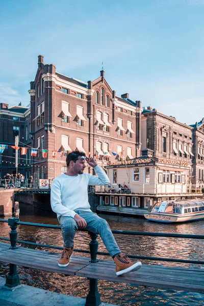 Amsterdam 'a şehir gezisine giden genç adam, Amsterdam kanallarını ziyaret eden eski kanal evi ve köprüsü olan adamlar. — Stok fotoğraf