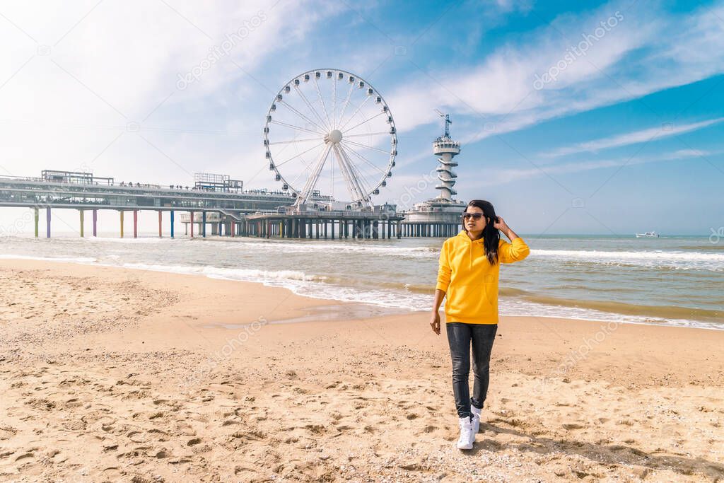 woman on the beach of Schevening Netherlands during Spring, The Ferris Wheel The Pier at Scheveningen in Netherlands, Sunny spring day at the beach