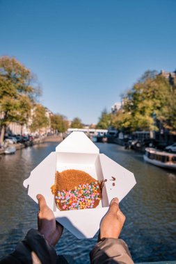 Amsterdam Hollanda, Amsterdam 'da Stroopwafel ile el ele tutuşan kadın - tipik Hollanda yemeği - karamel benzeri şurupla dolu iki dairesel waffle parçası