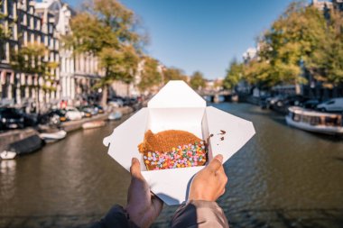Amsterdam Hollanda, Amsterdam 'da Stroopwafel ile el ele tutuşan kadın - tipik Hollanda yemeği - karamel benzeri şurupla dolu iki dairesel waffle parçası
