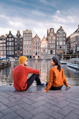 Amsterdam Damrak gün batımında, mutlu çift bir yaz akşamı kanallarda