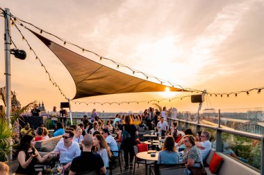 Amsterdam Hollanda Mayıs 2018 gün batımında şehir silueti, çatıdaki restoran barında insanlar gün batımını izliyor