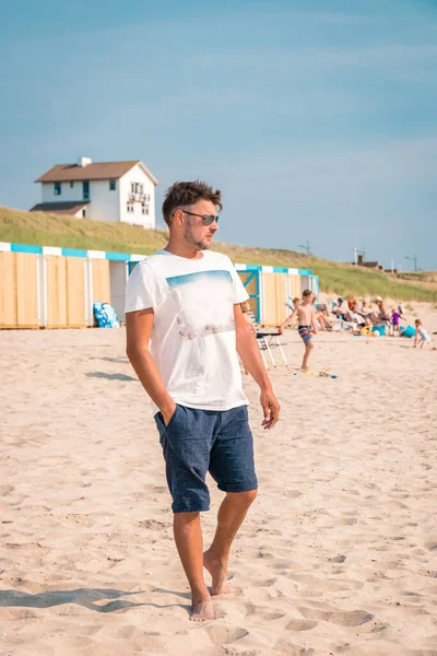 Bergen aan Zee Netherlands sahilinde yürüyen genç adamlar Bergen aan Zee Holland plajında mavi beyaz bir sahil kulübesi var. — Stok fotoğraf