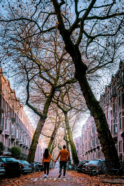 Amsterdam Holandia, para spacerująca po pięknej ulicy Lomanstraat w Amsterdamie jesienią z pochylonymi drzewami — Zdjęcie stockowe