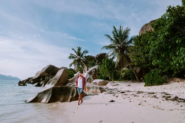 La Digue Seychellen, jonge mannen wandelen aan het witte strand met helderblauwe oceaan op vakantie op het tropische eiland — Stockfoto