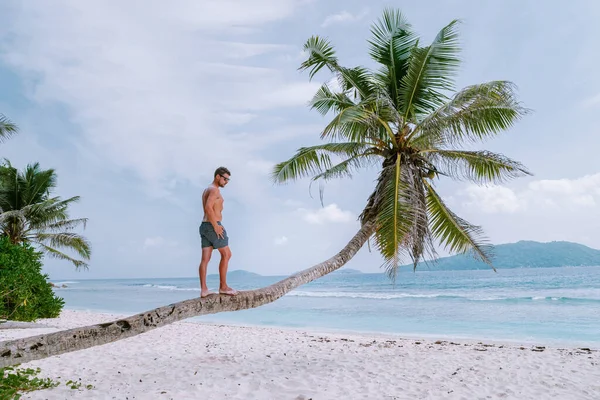 La Digue Seyşeller, tropikal adada açık mavi okyanusla beyaz sahilde yürüyen genç adamlar. — Stok fotoğraf