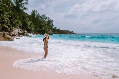 Petite Anse Mahe Seyşeller, sahilde genç bir kadın, tropik sahilde yürüyen orta yaşlı Asyalı kadın Seyşeller.