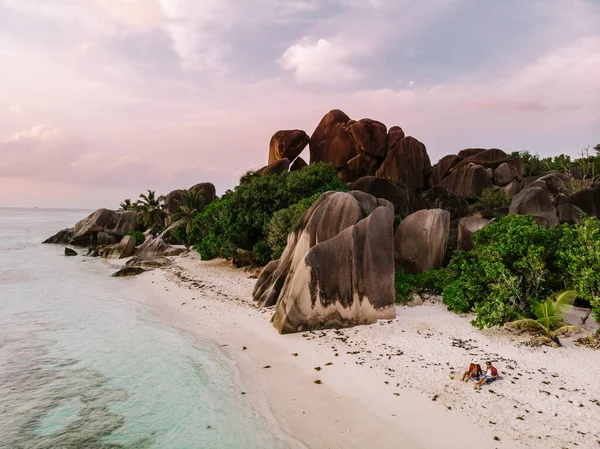 Widok drona na białą plażę ze szczęśliwą młodą parą spacerującą po plaży nad oceanem z palmami na Seszelach La Digue — Zdjęcie stockowe