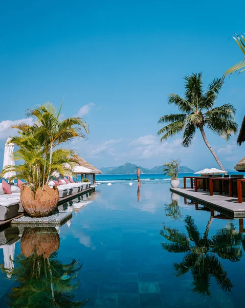 Hombres jóvenes en la piscina durante el atardecer, piscina de lujo en el complejo tropical, vacaciones relajantes en las islas Seychelles. La Digue, Joven al atardecer en la piscina — Foto de Stock