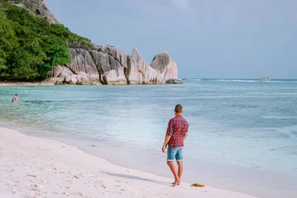 La Digue Seychely, mladí muži na dovolené na tropickém ostrově La Digue, muž středního věku procházky na pláži během dovolené na tropické pláži Seychely — Stock fotografie