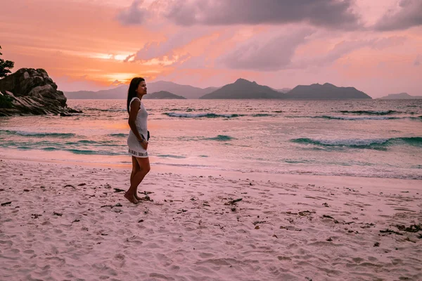 La Digue Seychellen, Sonnenuntergang am weißen tropischen Strand mit Palme, junge Frau im Urlaub auf den Seychellen, Luxusurlaubsziel Mädchen am weißen Strand — Stockfoto