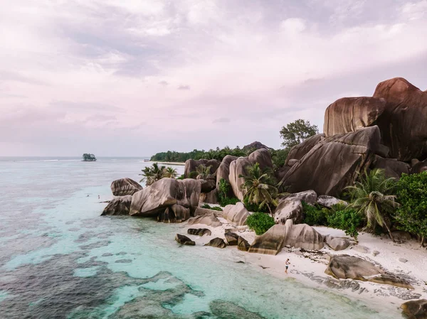 Drone vista sulla spiaggia bianca con felice Giovane coppia a piedi sulla spiaggia in riva al mare con palme alle Seychelles La Digue — Foto Stock