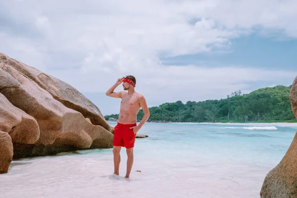 Cote dOr Beach Praslin Seychellerna, unga medelålders män i simma kort promenad på stranden under semester Secyhelles tropiska ön, vit kille på stranden under semestern Praslin — Stockfoto