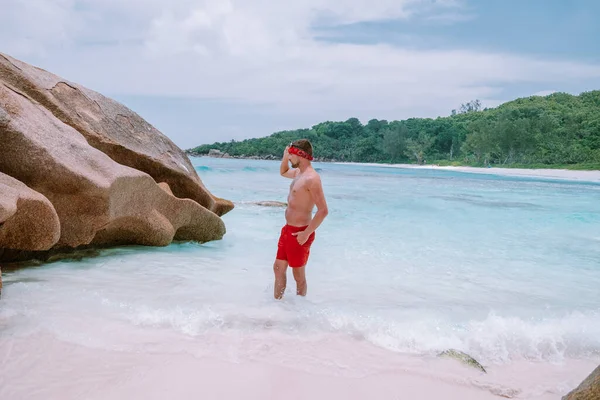 Cote dOr Beach Praslin Seychellerna, unga medelålders män i simma kort promenad på stranden under semester Secyhelles tropiska ön, vit kille på stranden under semestern Praslin — Stockfoto