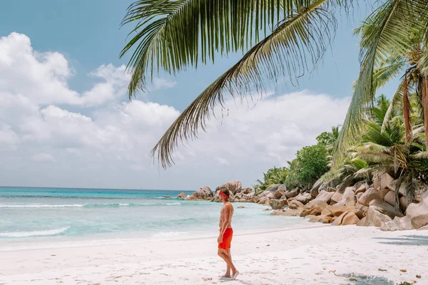 Cote dOr Beach Praslin Seszele, młodzi mężczyźni w średnim wieku w kąpieli krótki spacer po plaży podczas wakacji Secyhelles tropikalna wyspa, biały facet na plaży podczas wakacji Praslin — Zdjęcie stockowe