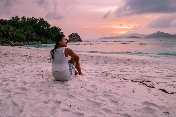 La Digue Seszele, zachód słońca na białej tropikalnej plaży z palmą, młoda kobieta na wakacjach na Seszelach, luksusowa dziewczyna na białej plaży — Zdjęcie stockowe