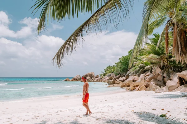 Côte dOr Plage Praslin Seychelles, jeunes hommes d'âge moyen en nage courte marche sur la plage pendant les vacances Secyhelles île tropicale, blanc sur la plage pendant les vacances Praslin — Photo