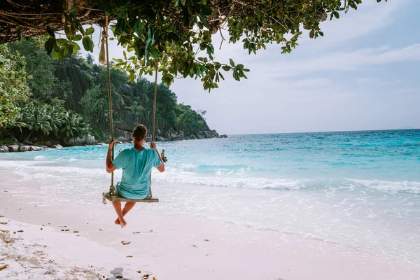 在塞舌尔热带岛屿La Digue度假的年轻人，在塞舌尔热带海滩度假期间在海滩散步的中年男子 — 图库照片