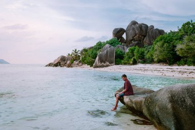 La Digue Seyşeller, tropik ada La Digue 'da tatilde olan genç erkekler, tropik sahil Seyşelleri' nde tatilde sahilde yürüyen orta yaşlı bir adam.
